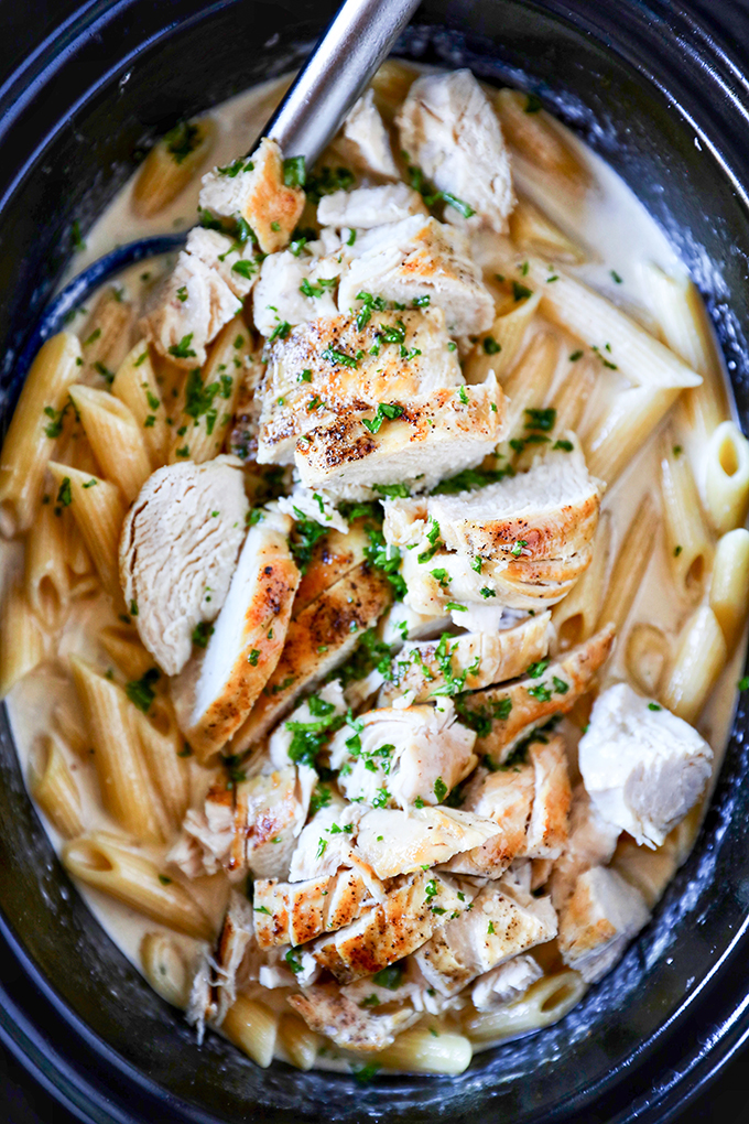 This Slow Cooker Chicken Alfredo is so easy to make. Tender juicy chicken breasts cooked right in a flavorful homemade alfredo sauce and the pasta cooks right in the slow cooker!